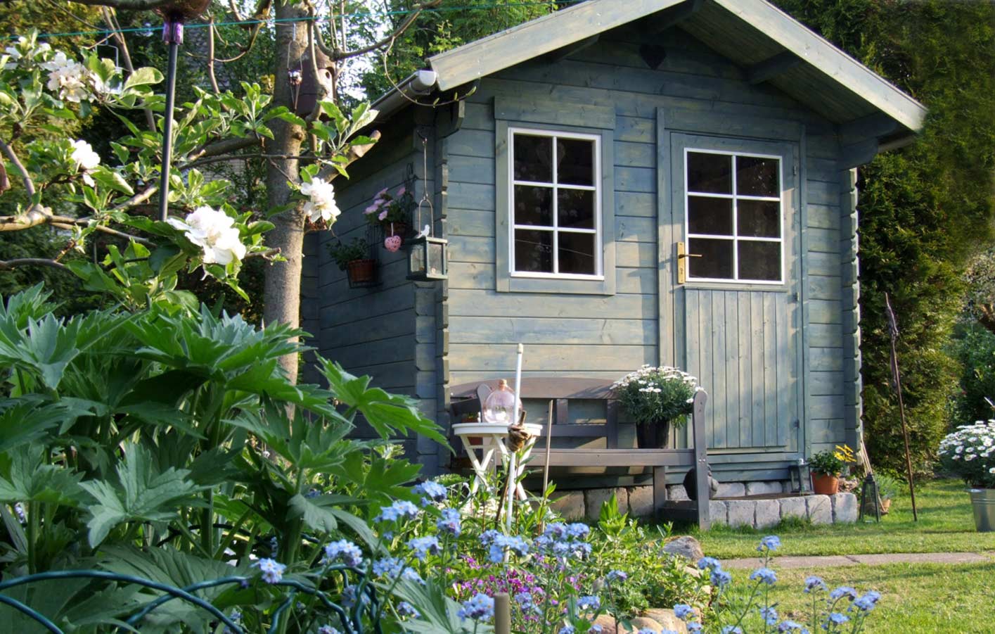 graues Gartenhaus in einem grünen Garten